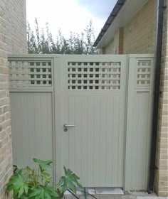 a gate is shown in front of a brick building with a plant next to it