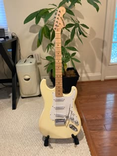 an electric guitar sitting next to a potted plant