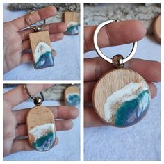 a person holding a wooden keychain with a painting on it's side