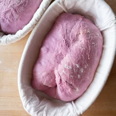 two bowls filled with pink colored dough on top of a wooden table next to each other