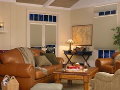 a living room with two couches, chairs and a coffee table in front of windows