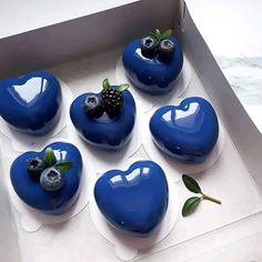 six blue heart shaped cakes with berries on top in a box, ready to be eaten