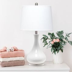 a white lamp sitting on top of a table next to a vase filled with flowers