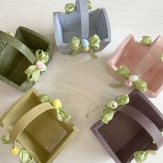 four small wooden boxes with bows on the handles and ribbons around them, all decorated in different colors