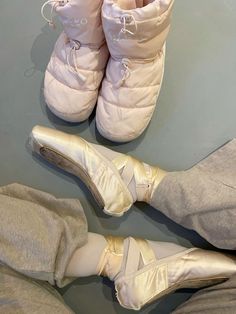 two pairs of white shoes sitting next to each other on top of a gray floor