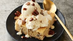 a black plate topped with ice cream and pecans