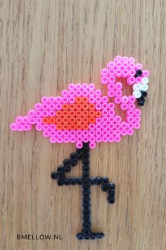 a pink flamingo made out of legos sitting on top of a wooden table