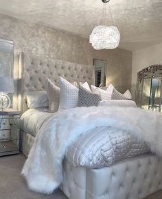 a bed with white fur and pillows in a bedroom