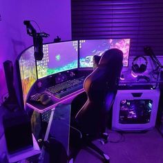 a computer desk with two monitors and a keyboard in front of purple lights on the wall