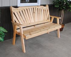 a wooden bench sitting in front of a window next to a potted green plant