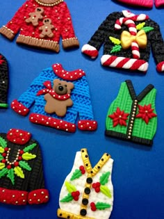 decorated cookies are arranged on a blue surface with red, white and green sweaters