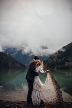 a man and woman standing next to each other in front of a lake