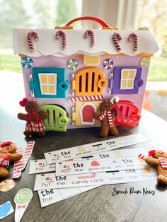 the gingerbread house is next to some candy canes and paper cut outs on a table