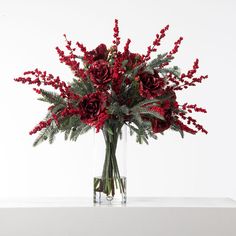 a vase filled with red flowers and greenery