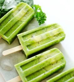 three popsicles with green toppings sitting on top of an ice block next to minty greens