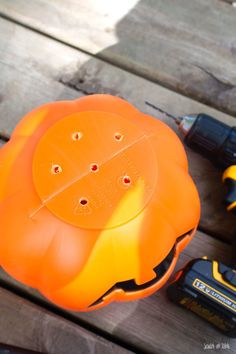 an orange flower shaped object sitting on top of a wooden table next to drillers