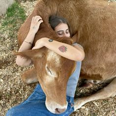 a woman is hugging the head of a brown cow with tattoos on it's arms