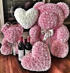 a teddy bear made out of pink roses and two bottles of wine are sitting on the floor