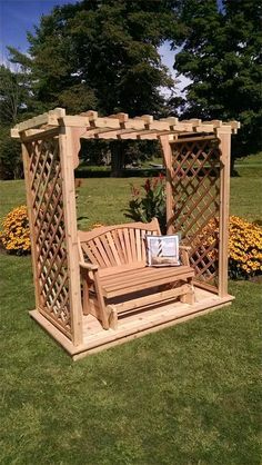 a wooden bench sitting in the middle of a field next to a gazebo and flowers