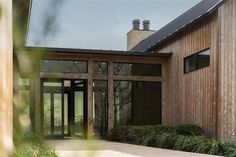 a large wooden building with glass doors and windows on the outside, surrounded by greenery