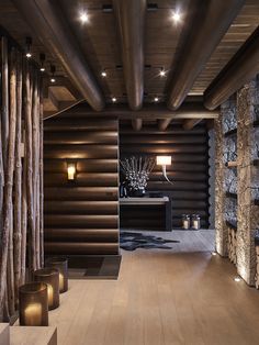 the interior of a modern log cabin with wood floors and stone walls, lit by lights