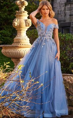 a woman in a blue dress standing next to a fountain