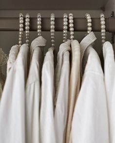 there are many white dresses hanging on the rack in front of some lace and pearls