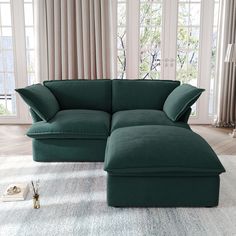 a large green couch sitting on top of a white rug in front of a window