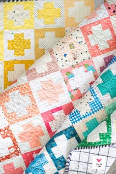 two quilts are laying next to each other on the ground, one has an orange and yellow patchwork design