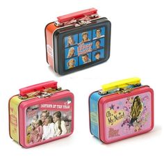 three tin lunch boxes with pictures of people on the front and back, one in pink, one in blue