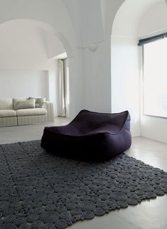 a black bean bag chair sitting on top of a rug