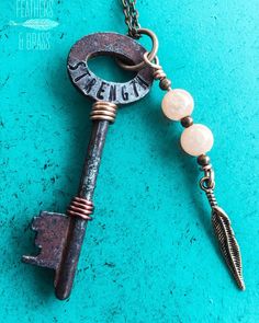 an old key is hanging from a chain on a turquoise background with the word genga written on it