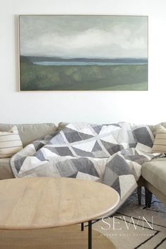 a living room with a couch, coffee table and painting on the wall above it