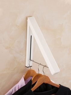 three shirts hanging on a clothes rack next to a wall mounted mirror and coat hanger