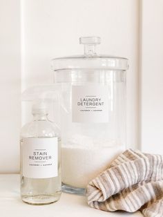 a bottle of laundry deterant next to a towel and glass container on a counter