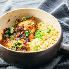 a bowl filled with rice and meat on top of a blue towel next to a fork