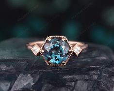 a blue diamond ring sitting on top of a black rock with two diamonds around it