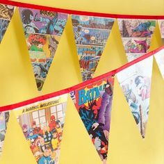 a bunch of flags that are hanging from a line on the wall in front of a yellow wall