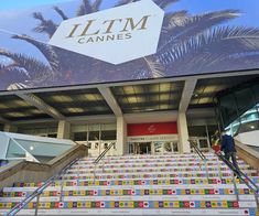 an escalator in front of a large building with palm trees on it's side