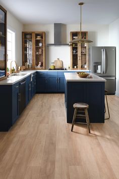 a large kitchen with blue cabinets and wooden flooring, along with a bar stool