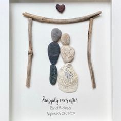 a white frame with rocks and driftwood in it that says happily ever after on the front