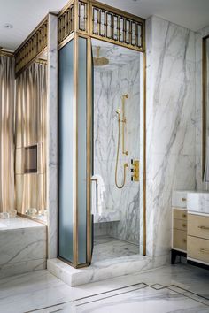 a bathroom with marble walls and flooring has a walk in shower next to the tub