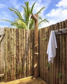 a wooden fence with a towel hanging on it and a palm tree in the background