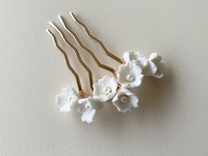 "PR1002 DAINTY FLORAL HAIR COMB Elegant and dainty floral wedding hair comb that has been made with love by Rositas! This hair piece features porcelain flowers and pearl beads carefully hand wired onto a gold hair pin. Suitable for weddings, proms, or any other special occasions. If you are looking for a simple yet classy look, this hair comb is for you!  PRODUCT DETAILS Dimensions are approximately 2.75\" (7 cm) (W) x 3\" (8 cm) (H) PRODUCTION Each hair piece is handmade to order and therefore Porcelain Hair Accessories, Polymer Clay Bridal Hair Accessories, Flower-shaped Polymer Clay Wedding Earrings, Wedding Headband Porcelain Flowers, White Floral Hair Piece, Wedding Flower Hair Pieces, Floral Wedding Hair, Gold Hair Comb, Gold Hair Pin