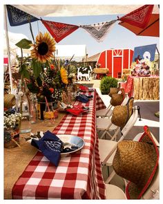 an outdoor table set up with red and white checkered cloths, sunflowers and other decorations