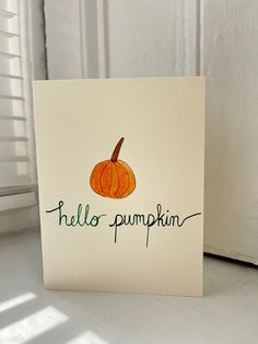 a card with the words hello pumpkin written on it and an orange pumpkin sitting in front of a white door