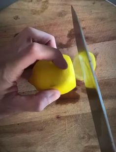 a person cutting up a lemon on top of a wooden table