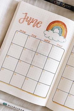 an open planner with a rainbow drawn on it and the word june written in cursive writing