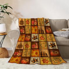 an autumn themed blanket with pumpkins, leaves and checkered squares on it in front of a couch