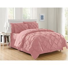 a bed with pink comforter and pillows in a room